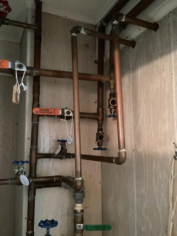 Responded to recurring winter pipe burst issue at outdoor shower location. Replaced failed piping system with copper pipe installation to prevent future freeze damage. New copper distribution system includes multiple branch lines with isolation valves, pressure regulation components, and proper mounting hardware secured to interior wall structure, while exterior connections feature upgraded PVC configuration with winterization capabilities.