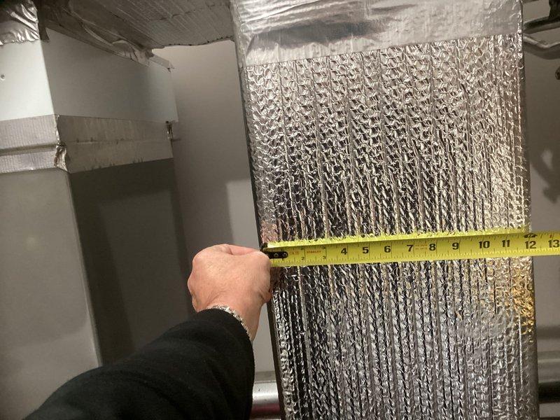 Conducted estimate assessment for downstairs HVAC system replacement in residential garage location. Documented existing equipment configuration including furnace unit and ductwork with reflective insulation, measuring duct dimensions and photographing current installation layout to prepare comprehensive replacement proposal.
