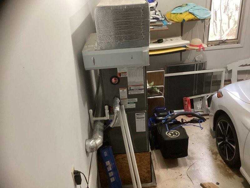 Conducted estimate assessment for downstairs HVAC system replacement in residential garage location. Documented existing equipment configuration including furnace unit and ductwork with reflective insulation, measuring duct dimensions and photographing current installation layout to prepare comprehensive replacement proposal.