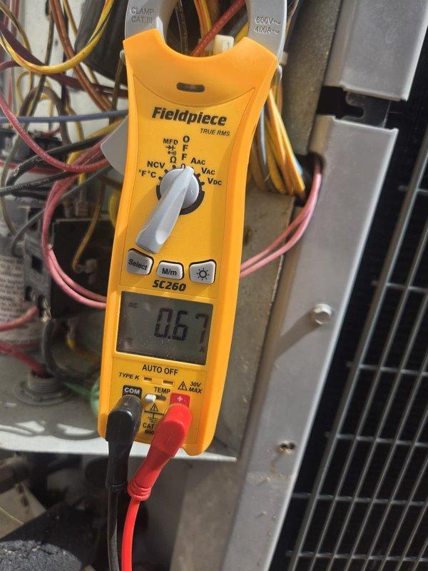Performed routine preventive maintenance on residential cooling system. Used digital multimeter to verify electrical readings and proper voltage levels across system components, confirming all measurements within manufacturer specifications at 0.67 reading. Checked temperature differential and system operation using calibrated temperature probe to ensure adequate cooling performance and proper refrigerant cycle function.