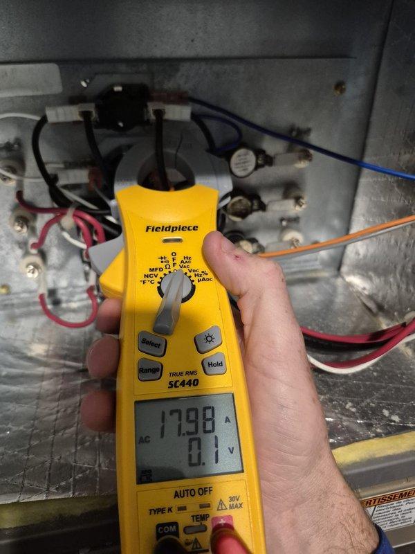Responded to no heat call on system less than 10 years old that was running but failing to reach setpoint. Upon arrival, performed diagnostic testing using digital multimeter to measure system voltage and amperage. Initial voltage reading showed 35.42V at blower motor assembly, indicating potential low voltage issue. Further testing revealed amperage draw of 179.8A, which is significantly elevated and indicative of a locked rotor or failing motor condition. Inspected interior components including copper refrigerant lines, electrical connections, blower motor housing, and wiring harnesses. Found blower motor drawing excessive current while attempting to operate, causing system to run continuously without adequate air circulation to satisfy thermostat demand. The elevated amperage reading confirmed motor failure, preventing proper heat distribution throughout the space. Documented findings with photos showing diagnostic meter readings and internal equipment condition for service records.