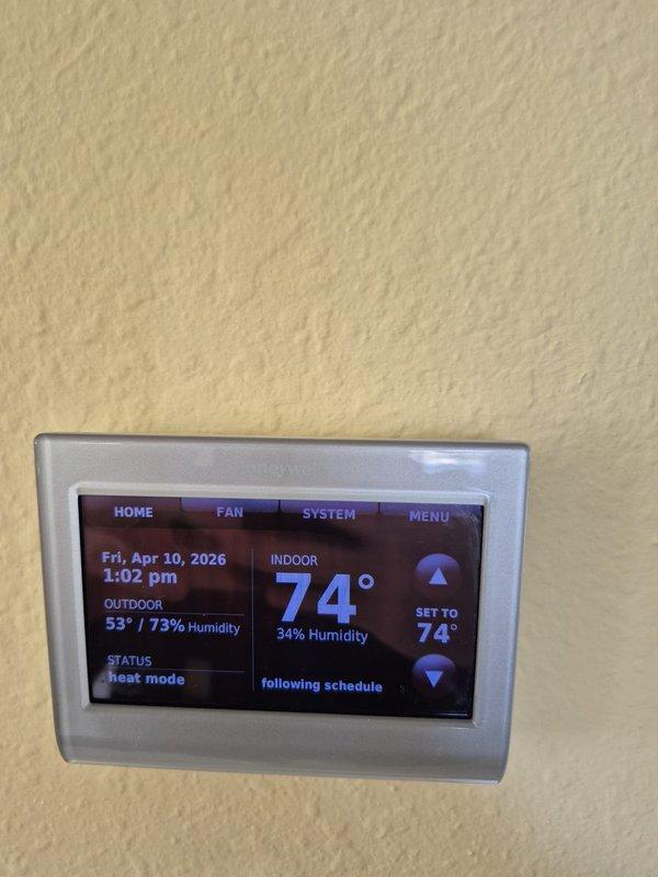 Completed preventive maintenance on cooling system. Verified thermostat operation showing indoor temperature at 74°F with 34% humidity and confirmed proper system scheduling in heat mode. Measured electrical parameters using clamp meter, recording 133.1 amp reading at outdoor unit, and inspected all electrical connections and wiring for proper operation.