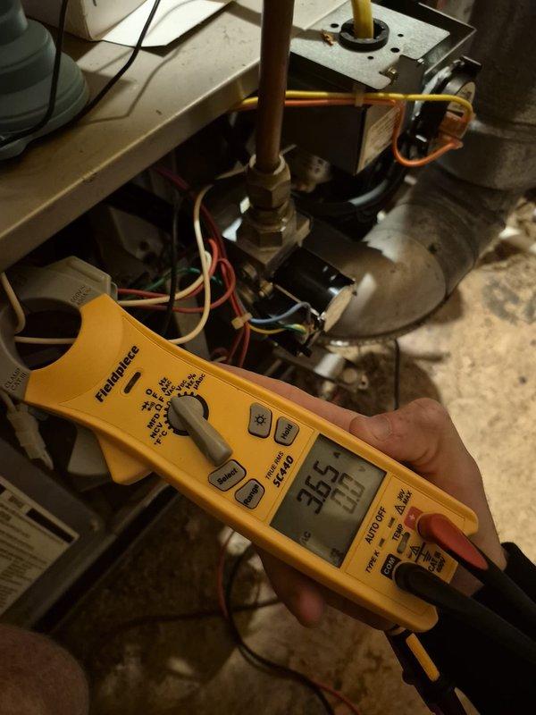 Performed cooling system maintenance and diagnostics on two HVAC units. Verified thermostat operation on Honeywell Home ProSeries unit displaying proper temperature readings and confirmed system settings in off mode with fan set to auto. Measured and recorded electrical voltage at 365V on system components using digital multimeter to ensure proper power supply to compressor and associated equipment.