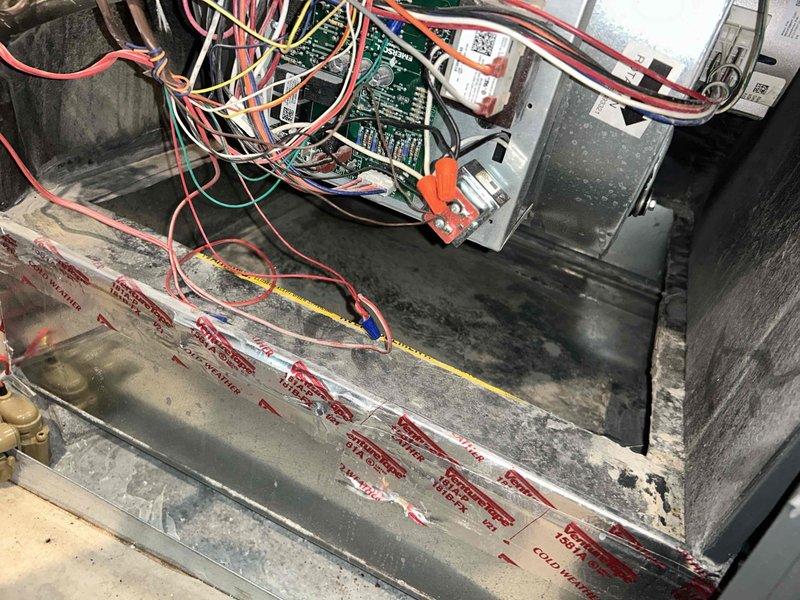 # HVAC Maintenance - Cooling System Service

Completed comprehensive cooling maintenance visit on residential HVAC system. Upon arrival, performed thorough inspection of air handler unit and associated components. Visual assessment revealed significant deterioration and contamination throughout the interior of the air handler cabinet, with extensive dark staining and discoloration on metal surfaces indicating prolonged moisture exposure and microbial growth. The blower housing compartment displayed heavy black and dark gray staining consistent with mold or mildew accumulation.

Inspected electrical connections and control wiring at the circuit board. Multiple colored wires including red, yellow, orange, and green conductors were present and routed through the upper section of the unit. Verified all electrical connections for proper termination and security at the green control board.

Examined condensate drainage system and drain pan assembly. The rectangular metal drain pan showed a d