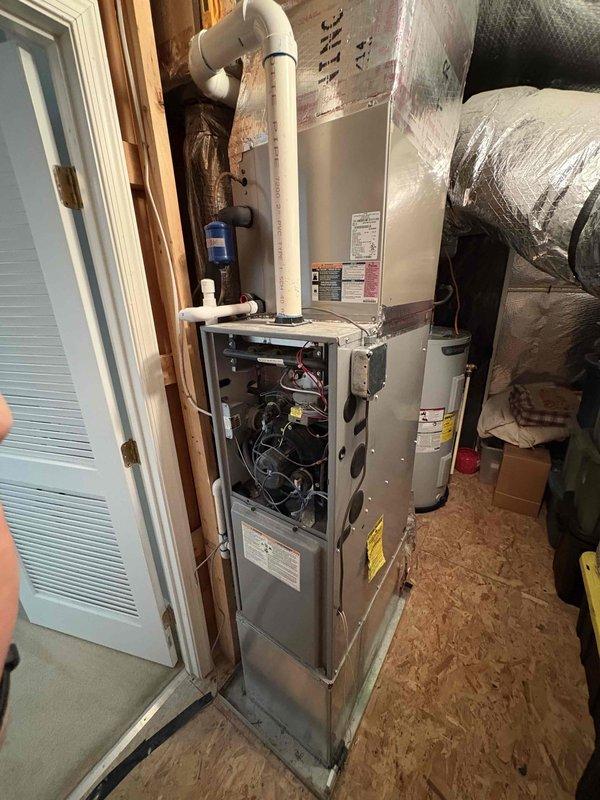 Responded to no cooling complaint on residential HVAC system. Upon arrival, accessed vertical furnace unit in attic space and inspected air handler with front panel removed. Evaluated internal components including wiring, circuit boards, and mechanical parts. Examined refrigerant system connections and blue filter drier component mounted to air handler. Verified PVC condensate drainage system and flexible ductwork connections. Documented equipment condition with photographs showing system configuration and component accessibility. System appears to be less than 10 years old based on equipment condition and labeling.
