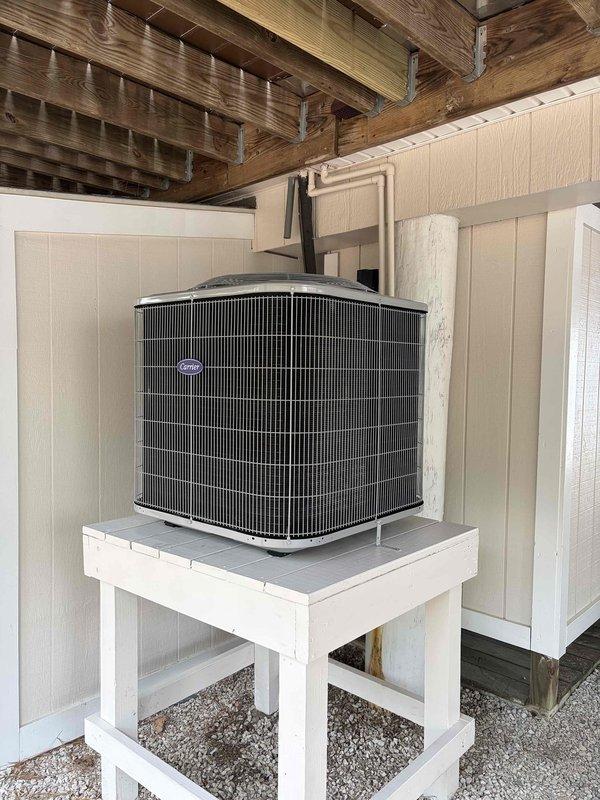 Completed full HVAC system replacement including installation of Carrier 27SCA536A003 3-ton 15 SEER heat pump, Carrier FT5ANBC36L00 variable speed air handler with 10kW electric heat pack, and Honeywell S1200 thermostat in black. Removed and disposed of existing equipment, with outdoor unit temporarily removed to allow contractor access for stand repair before final placement. Installed new outdoor disconnect and electrical whip, reused existing condensation and power lines, and fabricated metal duct transitions to adapt to existing ductwork. Rerouted flex duct line to improve airflow distribution to bedroom while maintaining system efficiency, positioned outdoor unit on repaired stand with proper clearance, and verified all electrical connections and refrigerant lines for proper operation.
