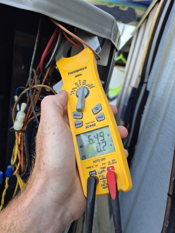 Performed routine cooling system maintenance and inspection. Verified electrical measurements at the outdoor unit, recording compressor amperage at 20.2 amps and confirming proper voltage at 6.19 volts across control circuits. All electrical connections inspected and found secure with no abnormalities detected in the condenser unit's electrical panel or wiring.