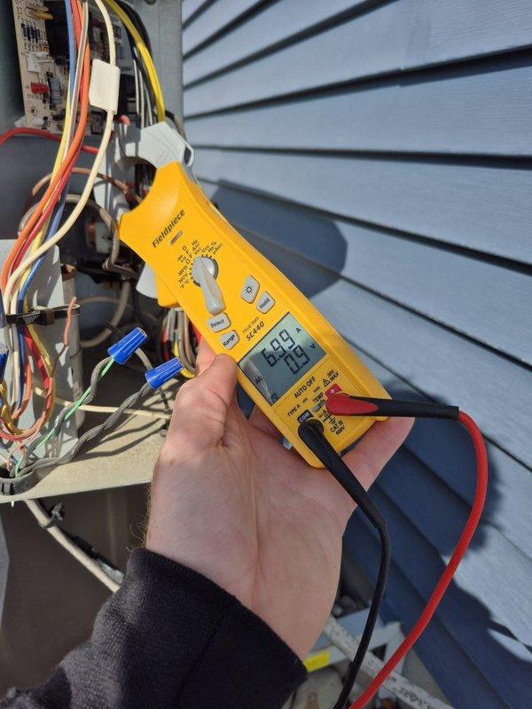 Completed preventive maintenance cooling visit on residential HVAC system. Verified thermostat operation showing proper temperature control and programming functionality, confirmed 24-volt control circuit voltage at outdoor unit measuring 24.5 volts, and inspected all electrical connections and wiring terminals for secure contact and proper operation.