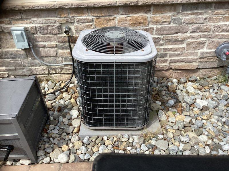 Performed diagnostic evaluation on 12-year-old residential HVAC system experiencing refrigerant loss. Found unit operating with critically low refrigerant charge, indicating leak in system. Given age of equipment, out-of-warranty status, and cost-effectiveness analysis, recommended complete system replacement rather than repair. Documented existing outdoor condenser unit with cylindrical configuration and indoor air handler/furnace system with associated ductwork and utility connections for replacement specifications.