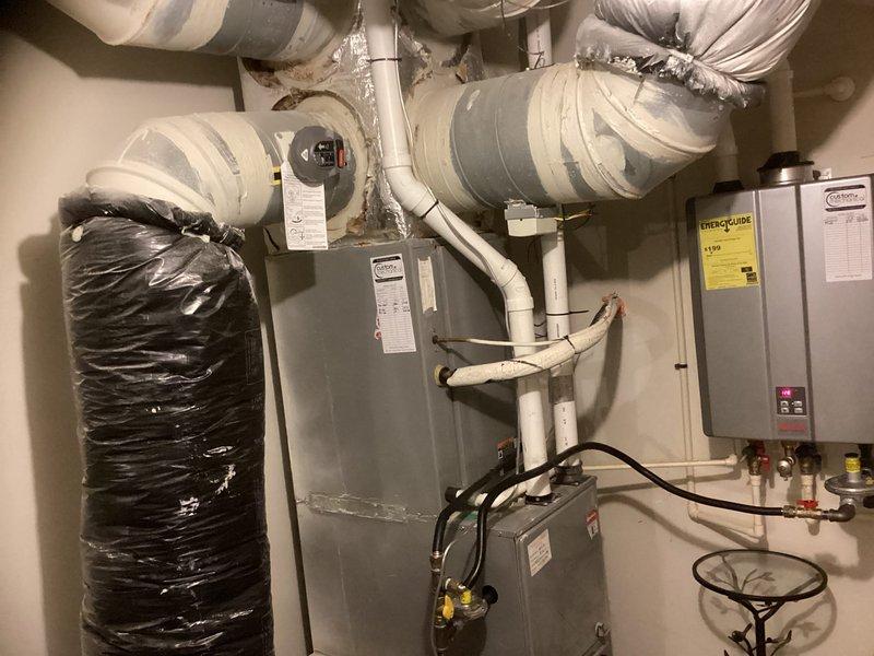 Performed diagnostic evaluation on 12-year-old residential HVAC system experiencing refrigerant loss. Found unit operating with critically low refrigerant charge, indicating leak in system. Given age of equipment, out-of-warranty status, and cost-effectiveness analysis, recommended complete system replacement rather than repair. Documented existing outdoor condenser unit with cylindrical configuration and indoor air handler/furnace system with associated ductwork and utility connections for replacement specifications.