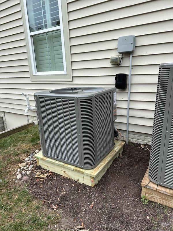 Completed full HVAC system replacement including removal and disposal of existing equipment. Installed Lennox EL297UH070E36 97% AFUE single-stage gas furnace with variable speed blower in basement crawl space. Mounted unit horizontally with proper condensate drainage using white PVC piping and connected yellow gas line. Fabricated and installed metal duct transitions to adapt new equipment to existing ductwork, with black insulated supply plenum visible in installation area.

Installed Lennox ML14KC1-042 3.5-ton 14 SEER air conditioner condenser unit on exterior of home. Positioned unit on pressure-treated wood platform for proper drainage and equipment protection. Replaced outdoor electrical disconnect and installed new electrical whip from junction box mounted on siding to condenser unit. Installed Lennox CK40DT-42B evaporator coil and LP conversion kit with furnace system.

Reused existing electrical service, condensate lines, and power supply connections where applicable to minimiz