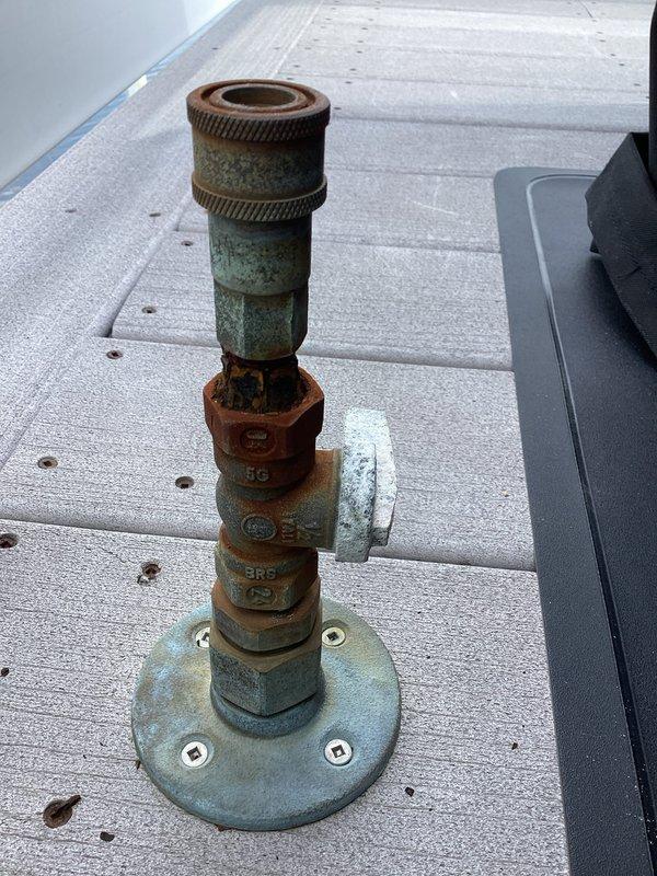 Completed de-winterization service for residential property with multiple outdoor water fixtures. Restored two outdoor shower systems to operational status by activating water supply lines, opening main shutoff valves, and pressurizing the plumbing system. Inspected rooftop plumbing assembly showing significant weathering and corrosion on copper components with verdigris oxidation present on base sections. Examined ground-level PVC distribution system beneath deck structure, verified proper operation of brass ball valves and control points, and confirmed water flow through all connection points. All outdoor water fixtures tested and confirmed operational for seasonal use.