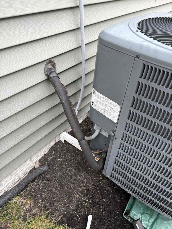 Responded to service call for outdoor HVAC unit experiencing operational noise and incomplete refrigerant line insulation per home inspection findings. Upon arrival, inspected condensing unit and discovered significant deterioration of black foam insulation on copper refrigerant lines, with extensive cracking, splitting, and gaps exposing bare copper tubing throughout the vertical run along exterior wall. Documented weathered and fragmented insulation condition showing age-related degradation. Evaluated unit operation and assessed noise complaint in conjunction with compromised line insulation. Photographed deteriorated insulation on refrigerant lines and overall system installation for documentation purposes.
