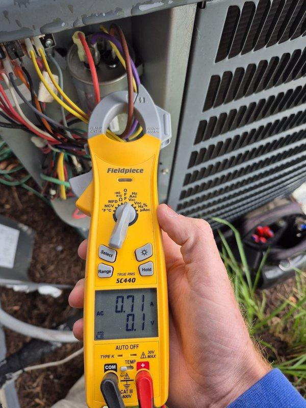 Performed routine cooling maintenance visit on residential HVAC system. Verified thermostat operation showing system in off mode with proper display functionality. Conducted electrical diagnostics on outdoor condensing unit using clamp meter to measure amperage and confirm proper electrical performance of compressor and fan motor circuits.
