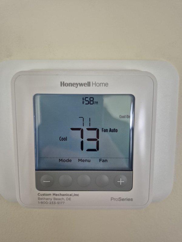 Performed cooling system tune-up and maintenance check on residential HVAC unit. Verified thermostat operation showing system cooling to 73°F setpoint with fan in auto mode. Took electrical measurements using clamp meter at control board, confirming proper amperage draw and system performance. Replaced 16x25x4 air filter as part of routine maintenance to ensure optimal airflow and system efficiency.