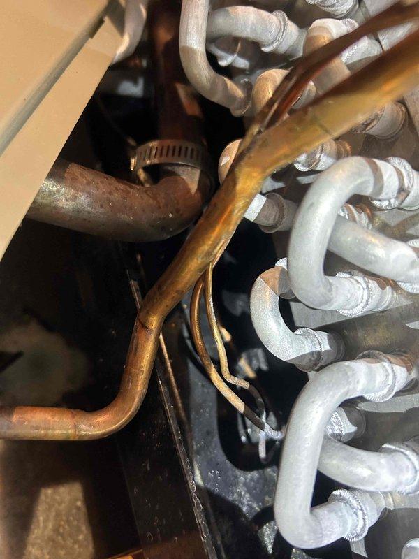 Responded to a system with inadequate cooling performance. Upon arrival, diagnosed low refrigerant charge indicated by a 9-degree temperature split across the evaporator coil. Added 4 ounces of R-410a refrigerant with UV dye to the system, which improved suction pressure to 177 PSI. Temperature readings confirmed restricted refrigerant flow through the evaporator coil. Further diagnosis identified a faulty thermostatic expansion valve (TXV) requiring replacement. Ordered replacement TXV part number D346317P49 for follow-up repair visit. System requires TXV replacement and completion of maintenance service to restore proper cooling capacity. Unit total refrigerant capacity is 9.6 pounds of R-410a excluding line set volume.