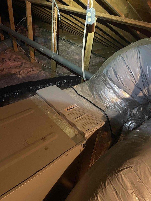 Performed seasonal cooling system maintenance check on outdoor condensing unit and indoor air handling equipment. Inspected R410A outdoor unit showing normal weathering, verified nameplate specifications and serial number documentation, and examined attic-mounted HVAC components including supply ductwork and insulated flex runs for proper installation and condition.