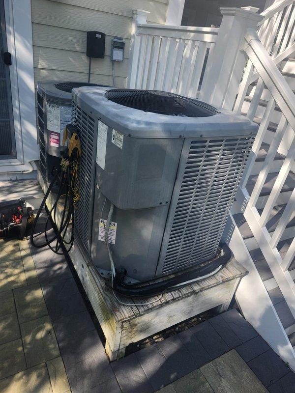 Responded to no cooling complaint on residential split system. Upon arrival, connected manifold gauges to outdoor condensing unit and performed system diagnostics. Unit was not maintaining set temperature as reported. Completed refrigerant pressure testing and system evaluation to identify cause of inadequate cooling performance. Documented equipment condition with photos showing dual condensing units installed on exterior deck platform with testing equipment connected during diagnostic process.