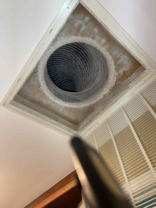 Performed seasonal cooling system maintenance check on HVAC unit. Upon arrival, disarmed security system as instructed and accessed property. Inspected Trane thermostat, which displayed proper operation in cooling mode with current settings at 70°F and programmed cooling setpoint at 72°F. Unit showed "WAIT" status indicating normal delay cycle protection. Examined triangular ceiling vent opening and noted significant accumulation of dust, dirt, and discoloration on mesh screen surrounding the black spiral ventilation duct. Documented conditions with photos showing staining and debris buildup around vent perimeter, which may impact air quality and system efficiency. Verified thermostat functionality and confirmed system responding appropriately to cooling demands. Rearmed security system upon completion of inspection.