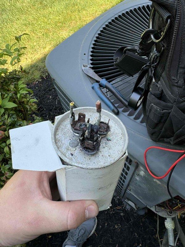 Responded to no cooling call on downstairs system with outdoor unit not operating. Upon inspection, found failed dual run capacitor with severe terminal corrosion and degradation. Replaced defective capacitor, verified proper electrical connections, and tested system operation. Unit restored to normal cooling function with proper amperage draw and temperature split confirmed.