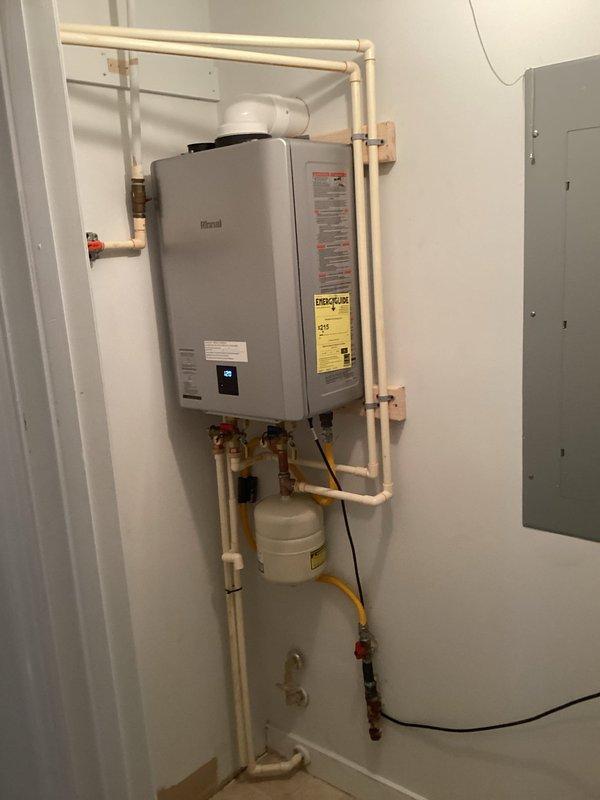 Completed full installation of Rinnai RX199iN1 tankless water heater system in utility room. Mounted unit to wall with proper clearances and connected to existing water supply lines using IPS service valves and copper piping with shut-off valves for isolation and maintenance access. Installed expansion tank to protect system from thermal expansion. Configured gas supply line using 3/4" x 5' flexible gas connector and black iron fittings including union, tee, reducer, nipples, cap, and brass ball valve for proper gas delivery and code compliance. Installed concentric venting system through exterior wall for combustion air intake and exhaust. Connected electrical supply and programmed unit settings. Integrated white PVC piping for condensate drainage. All connections pressure tested and verified leak-free. System activated, tested for proper operation, and confirmed adequate hot water delivery and temperature control. Installation meets manufacturer specifications and local plumbing code