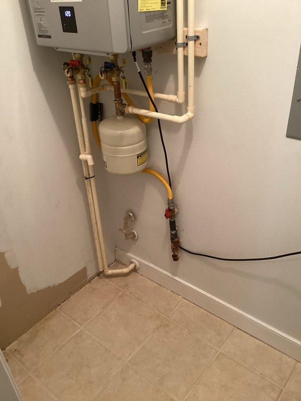 Completed full installation of Rinnai RX199iN1 tankless water heater system in utility room. Mounted unit to wall with proper clearances and connected to existing water supply lines using IPS service valves and copper piping with shut-off valves for isolation and maintenance access. Installed expansion tank to protect system from thermal expansion. Configured gas supply line using 3/4" x 5' flexible gas connector and black iron fittings including union, tee, reducer, nipples, cap, and brass ball valve for proper gas delivery and code compliance. Installed concentric venting system through exterior wall for combustion air intake and exhaust. Connected electrical supply and programmed unit settings. Integrated white PVC piping for condensate drainage. All connections pressure tested and verified leak-free. System activated, tested for proper operation, and confirmed adequate hot water delivery and temperature control. Installation meets manufacturer specifications and local plumbing code