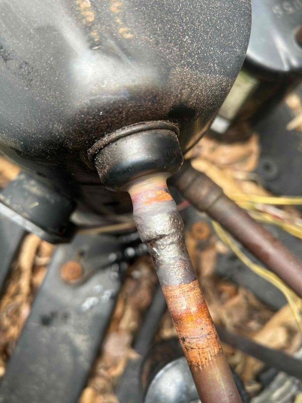 Responded to no cooling complaint on residential HVAC system. Upon arrival, performed diagnostic evaluation of outdoor condensing unit and refrigerant circuit. Utilized digital micron gauge to measure system vacuum levels, recording reading of 203 microns during assessment. Identified significant corrosion on refrigerant piping connections and compressor discharge line, with visible rust deterioration affecting system integrity. Observed moisture accumulation on compressor housing indicating potential leak or compromised seal. Evaluated refrigerant line set condition, noting proper insulation on suction and liquid lines. System required attention to corroded components affecting refrigerant containment and overall cooling performance.
