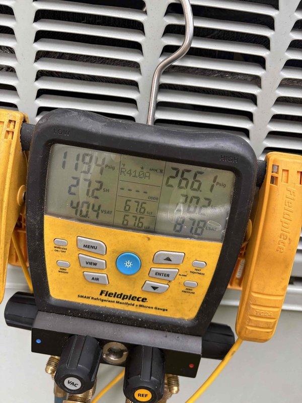 Responded to no cooling complaint on downstairs system. Accessed property through side entrance per instructions and located unit in basement area. Upon inspection, found system running but not cooling to desired temperature. Performed diagnostic testing using refrigerant manifold gauges to measure system pressures and temperatures across the evaporator coil. Readings indicated abnormal operating conditions with suction and discharge pressures outside normal parameters. Inspected electrical panel serving HVAC equipment, noting age-related deterioration with rust staining and multiple handwritten circuit identifications. Documented system conditions with photos of breaker panel and diagnostic gauge readings for service records. Advised that repair costs would be customer responsibility as unit age exceeds warranty coverage period, even with platinum level service agreement.