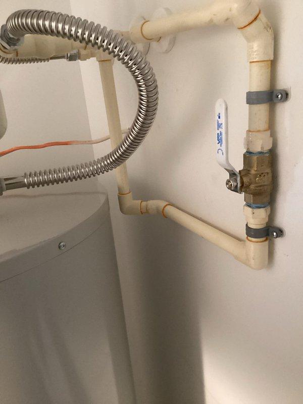 Installed a 50-gallon Bradford White tall water heater (model RE250T6) in residential property being prepared for rental. Positioned unit on 22-inch aluminum drain pan on laminate flooring in utility closet. Connected water supply lines using two 24-inch stainless steel flex connectors with appropriate brass fittings including 3/4" brass tee, 90-degree elbow, and nipples of varying lengths.

Relocated existing main water shut-off valve from top of previous heater location to new position beside tank at lower height for improved accessibility. Replaced old 3/4" CPVC ball valve with new 3/4" brass FIP ball valve. Fabricated and installed approximately 10 feet of 3/4" CPVC piping to accommodate new valve location using brass and CPVC fittings as needed.

Installed thermal expansion tank to protect plumbing system from pressure fluctuations. Integrated 3/4" male high-temperature dielectric union for proper connections. Secured all piping to wall using black plastic pipe clamps at multiple 