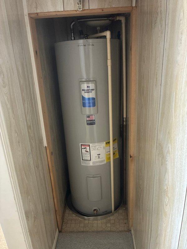 Replaced a 50-gallon tall electric water heater in a third-floor condo back bedroom closet. Installed new Bradford White unit with aluminum drain pan, expansion tank, brass fittings including T and 90-degree elbow, brass nipples, 18-inch flex connectors, male transition unions, SharkBite couplings, and SharkBite ball valve. Two-person crew completed installation in three hours with all connections secured and unit operational.