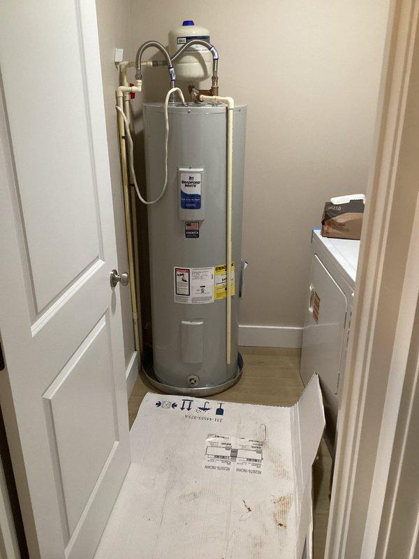Successfully installed a 50-gallon tall residential electric water heater (model RE250T61) in a utility closet. Installation included a 22-inch drain pan positioned beneath the unit, a white expansion tank with blue cap mounted on top and connected via stainless steel braided flex connectors, and all necessary brass fittings including 3/4" nipples (2" and 6"), 90-degree elbow, and tee fitting. Connected hot and cold water supply lines using 18-inch flexible connectors, installed pressure relief valve with proper discharge piping, and ensured all electrical connections were properly secured. All plumbing connections were tested for leaks and the unit was verified operational upon completion.