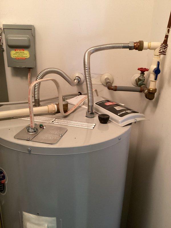 Performed routine maintenance inspection on residential tanked water heater system. Verified proper operation of all shutoff valves including red-handled and blue-handled ball valves, inspected flexible metallic connectors and PVC piping for signs of wear or deterioration, and examined compression fittings for corrosion or leaks. Confirmed water heater tank condition, checked electrical disconnect box, and documented existing patina on copper fittings. All components found to be in functional operating condition with no active leaks or immediate safety concerns identified.