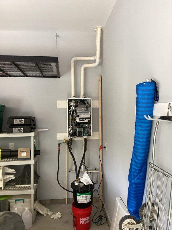 Performed preventive maintenance on wall-mounted tankless water heater unit, including flushing system with descaling solution using pump and bucket setup to remove mineral buildup from heat exchanger. Inspected all internal components, verified proper operation of burner assembly and venting system, and checked water and gas connections for leaks. Additionally discussed customer's request for future estimate to relocate utility sink in garage area.