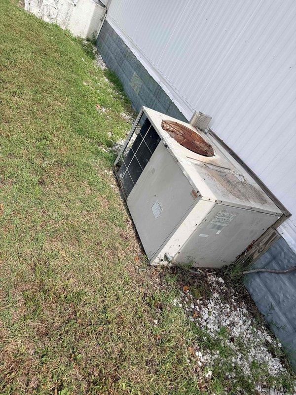Performed comprehensive evaluation of existing HVAC system at single-wide mobile home experiencing chronic freeze-up issues. Documented outdoor condensing unit showing significant age-related deterioration including extensive rust staining on top panel and fan grille area, weathered exterior surfaces, and overall system degradation. Assessed electrical panel configuration and circuit protection for existing system. Recommended complete system replacement due to unit's advanced age, recurring operational failures, and compromised equipment condition affecting reliability and efficiency.