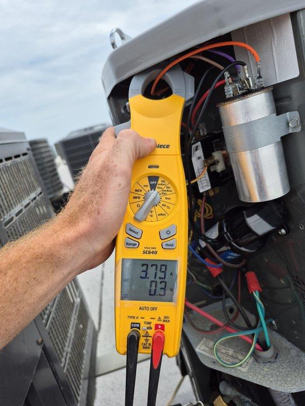 # HVAC Maintenance - Cooling System Service

Performed routine cooling maintenance visit on rooftop HVAC unit. Conducted electrical diagnostics using digital multimeter, measuring capacitor performance and electrical connections. Readings of 3.79 and 0.3 were recorded during testing. Inspected internal electrical components including cylindrical capacitor, contactors, and relay systems. Verified all wire connections, terminals, and color-coded wiring were secure and functioning properly. All components operating within normal parameters. Unit tested and left in proper working condition.