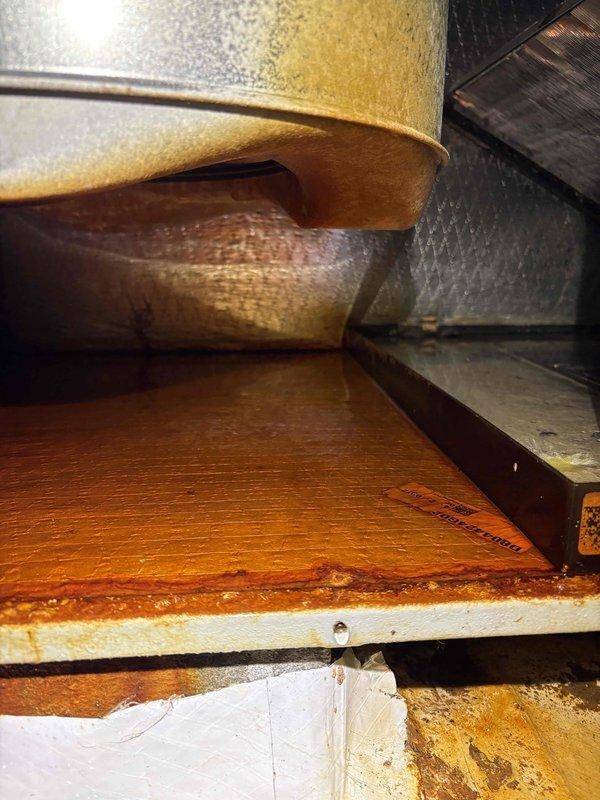 Responded to service call for HVAC unit leaking into crawlspace. Upon inspection, found excessive condensation accumulation on metal ductwork surfaces and significant water damage evident on concrete floor at duct junction with dark staining and moisture infiltration. Documented conditions showing condensation on rigid and flexible ductwork components, moisture buildup at seams, and biological growth at floor-to-duct interface indicating prolonged water intrusion issue. Customer notified of findings and advised of recommended corrective actions.