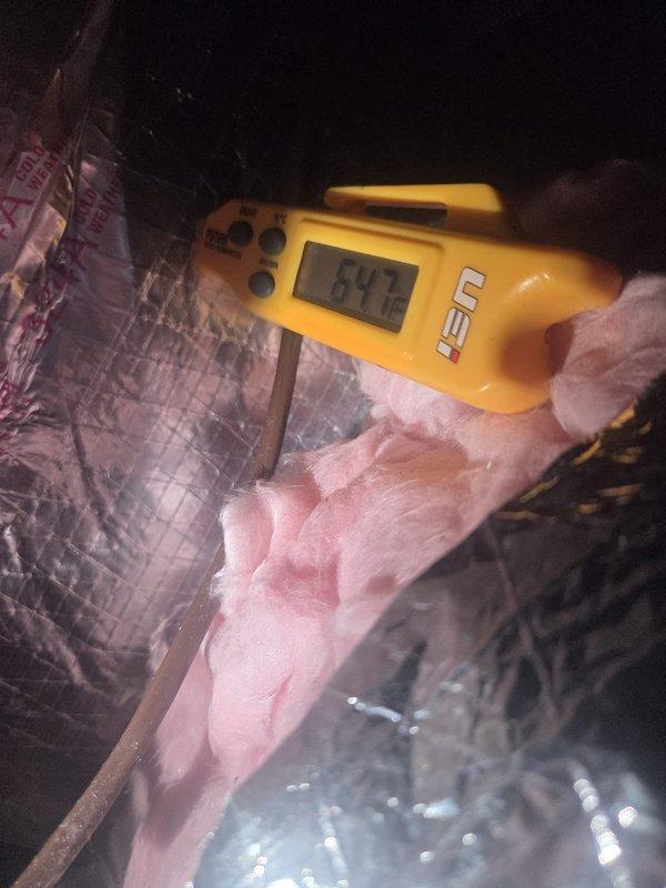 Responded to no cooling complaint on residential HVAC system less than 10 years old. Performed diagnostic testing in attic space using digital multimeter, obtaining temperature readings of 64.1°F at ductwork and insulation areas. Measurements taken at supply duct insulation and surrounding mechanical components to assess system performance and identify cooling deficiency cause.
