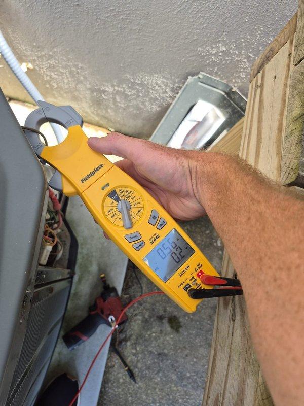 Performed routine HVAC maintenance and diagnostic testing on cooling system. Used clamp meter to measure electrical current draw and verify proper amperage readings on compressor and condenser unit, with measurements indicating system operating within normal parameters at 70.7-72.3 range. Inspected outdoor condenser unit components, wiring connections, and ductwork for proper operation and identified no issues requiring immediate attention.