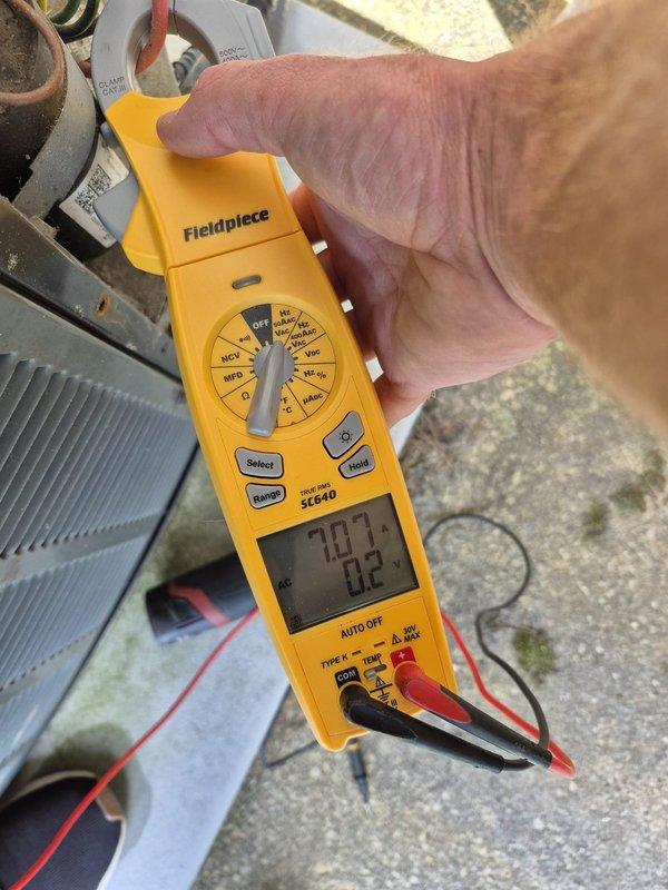 Performed routine HVAC maintenance and diagnostic testing on cooling system. Used clamp meter to measure electrical current draw and verify proper amperage readings on compressor and condenser unit, with measurements indicating system operating within normal parameters at 70.7-72.3 range. Inspected outdoor condenser unit components, wiring connections, and ductwork for proper operation and identified no issues requiring immediate attention.