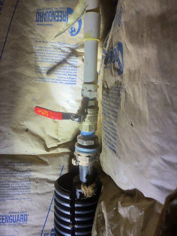 Responded to water leak investigation under residential structure near water heater and main shut-off valve. Upon inspection, identified failed pipe connection at plumbing assembly with compromised fitting integrity. Located source of leak at vertical pipe stack where brass fitting connected to deteriorated plastic pipe section showing significant wear and damage at connection point. Removed defective components including worn pipe segment with rough, damaged edges. Documented existing plumbing configuration featuring metal pipes, PVC sections, and ball valve assembly with evidence of previous repair attempts. Photographed failed components and overall system condition for reference. Recommended replacement of compromised fittings to restore system integrity and prevent continued water loss.