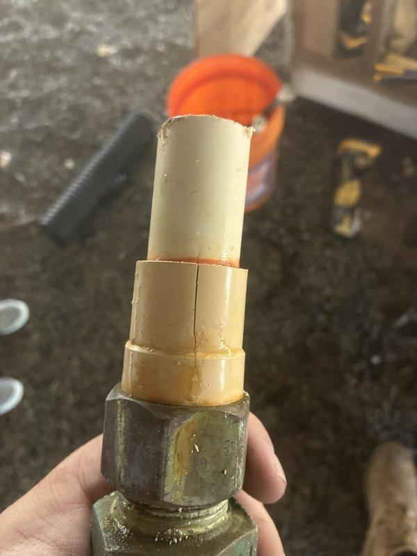 Responded to water leak investigation under residential structure near water heater and main shut-off valve. Upon inspection, identified failed pipe connection at plumbing assembly with compromised fitting integrity. Located source of leak at vertical pipe stack where brass fitting connected to deteriorated plastic pipe section showing significant wear and damage at connection point. Removed defective components including worn pipe segment with rough, damaged edges. Documented existing plumbing configuration featuring metal pipes, PVC sections, and ball valve assembly with evidence of previous repair attempts. Photographed failed components and overall system condition for reference. Recommended replacement of compromised fittings to restore system integrity and prevent continued water loss.