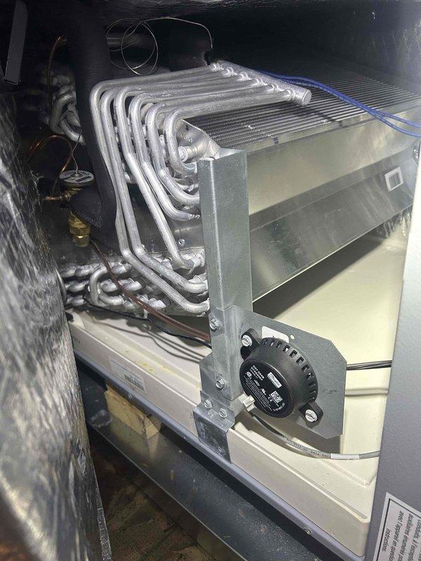 Responded to no cooling complaint on second floor geothermal system with inadequate airflow. Unit was reading 84°F against 78°F setpoint with 60% relative humidity. Upon inspection, accessed air handler in attic space and examined internal components including heat exchanger coil, blower motor assembly, and control wiring. Photographed serpentine heat exchanger showing clean coil surfaces and blower motor configuration. Documented control box and electrical connections for diagnostic purposes. Advised system be turned off temporarily to prevent compressor damage while operating without proper airflow.