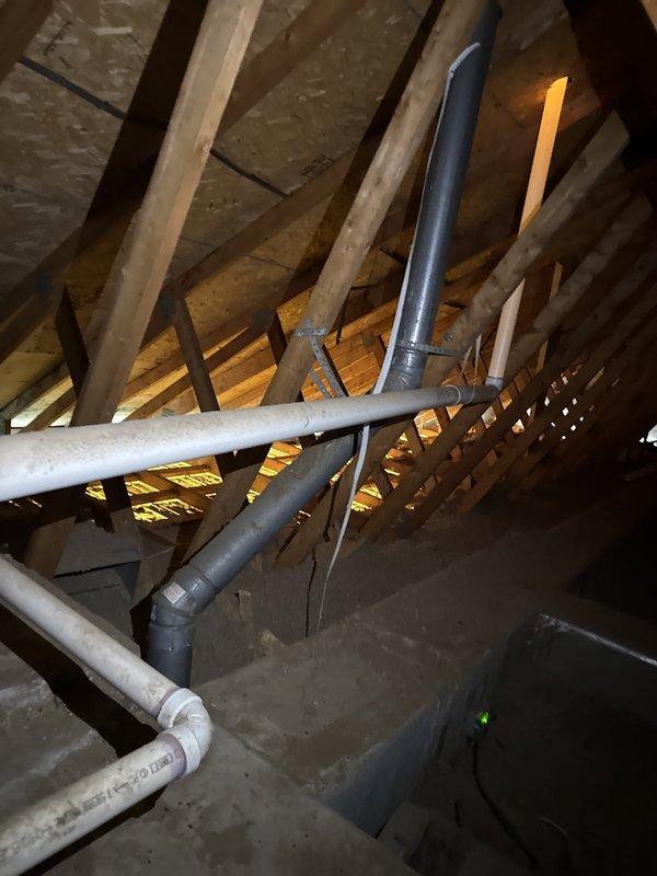 Conducted attic inspection to evaluate furnace flue pipe penetration through roof assembly. Assessed condition of existing metal flashing, storm collar, and termination cap on flue pipe system. Documented current installation of vent piping through roof structure and determined feasibility of replacing deteriorated metal components including top cap and roof sleeve assembly while maintaining proper clearances and weatherproofing integrity.