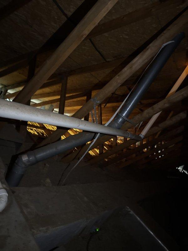 Conducted attic inspection to evaluate furnace flue pipe penetration through roof assembly. Assessed condition of existing metal flashing, storm collar, and termination cap on flue pipe system. Documented current installation of vent piping through roof structure and determined feasibility of replacing deteriorated metal components including top cap and roof sleeve assembly while maintaining proper clearances and weatherproofing integrity.
