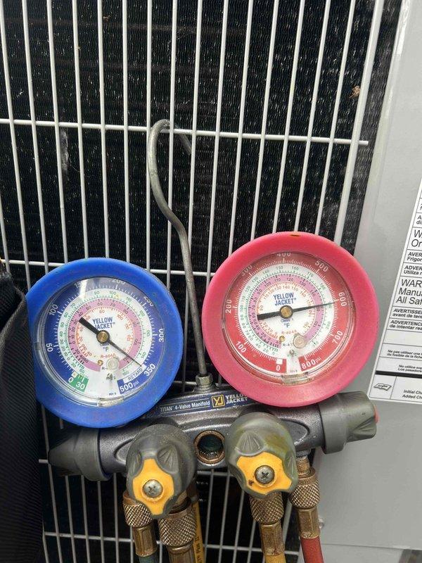 Responded to emergency service call for two-year-old air conditioning unit with complete system failure. Upon arrival, diagnosed critically low refrigerant charge with system nearly flat. Connected manifold gauges to verify pressures and added refrigerant along with UV dye to restore cooling operation and enable future leak detection. Given the age of the equipment and severity of refrigerant loss, recommended follow-up pressure test to identify leak source, as the charge may not hold long-term without proper repair of underlying issue.