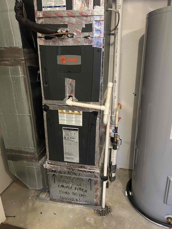 # HVAC Emergency Service - No Cooling Condition

Responded to emergency no-cool call on 10+ year old Trane air handler system. Upon arrival, performed diagnostic testing of electrical components using digital multimeter. Measured operating voltage at 348.5V and current draw at 0.47A to assess system performance. Inspected equipment installation in basement mechanical room, noting air handler mounted in metal framework alongside water heater. Verified unit specifications and reviewed maintenance labeling indicating 16x30 filter requirement with 30-day change interval. Documented equipment condition and diagnostic findings with photographic evidence. System evaluated for age-related component failure and cooling capacity issues typical of older HVAC installations.