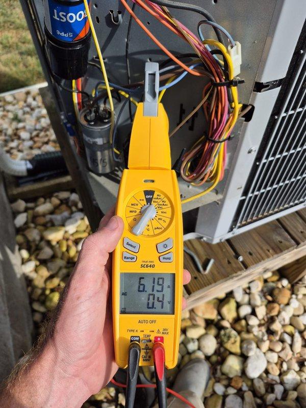 Arrived on-site for scheduled cooling maintenance visit on two HVAC systems. Customer was not present after 15-minute wait period, and multiple contact attempts via phone were unsuccessful with voicemails left on all available numbers. Documented electrical readings on outdoor condensing unit showing 6.19V and 0.4A using digital multimeter, and verified thermostat operation displaying 72°F indoor temperature with system set to cooling mode and fan on auto setting.