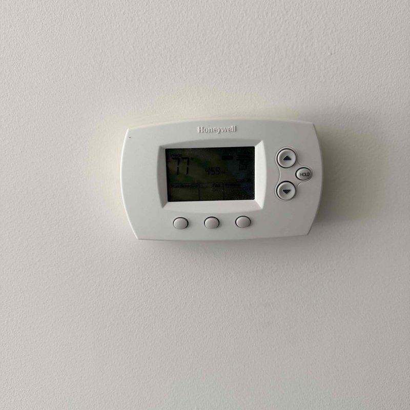 Assessed 14-year-old HVAC system with failed compressor located in interior utility closet. Documented existing vertically-stacked air handler unit with associated ductwork, electrical connections, and Honeywell digital thermostat control. Provided replacement system estimate as repair costs were determined to be prohibitive given equipment age and component failure.