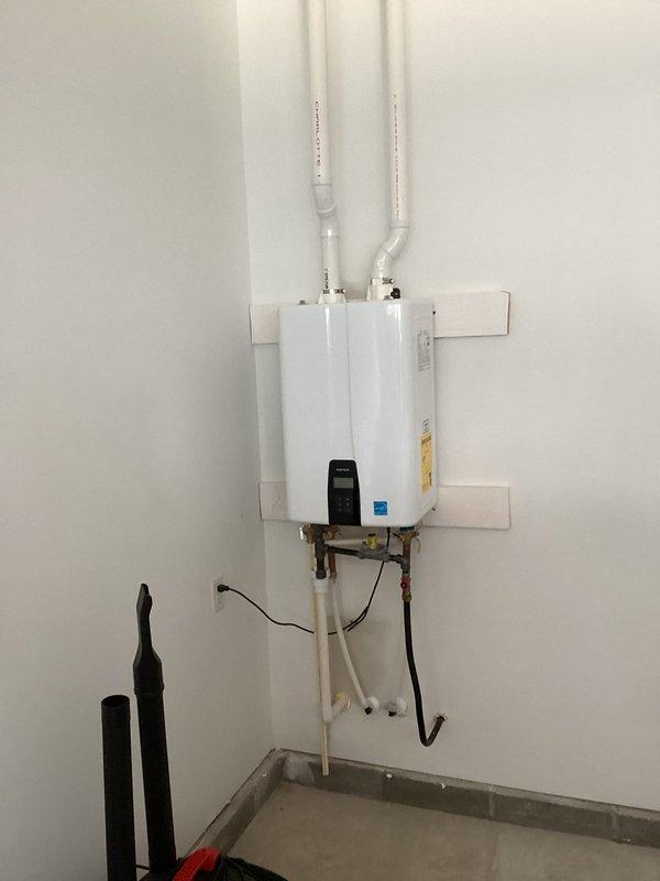 Responded to customer concern regarding watery, burning eyes potentially related to tankless gas water heater venting system. Performed comprehensive inspection of PVC venting pipes extending from unit through attic space to identify possible exhaust gas leakage or improper venting conditions. Examined all pipe connections, joints, and seals at the wall-mounted tankless water heater unit where dual white PVC intake and exhaust pipes connect. Verified proper installation of venting system, checked for separation at elbows and connection points, and assessed overall integrity of the venting pathway. Inspected copper water supply lines and electrical connections at unit base. Documented installation configuration with photographs for service records and customer reference.