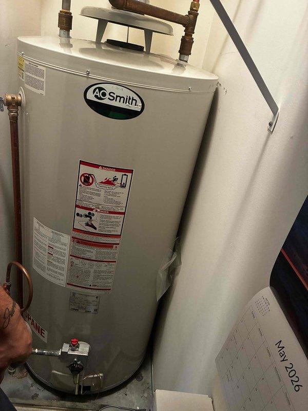 Conducted initial assessment and provided estimate for gas water heater replacement. Unit is an A.O. Smith model located in first-floor laundry room with easy access. Current system includes expansion tank mounted above water heater with copper supply lines and flexible connector hoses. Documented existing installation configuration including piping connections, control valve assembly, and electrical conduit routing for replacement planning.